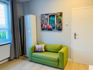 zielone krzesło w pokoju z obrazem na ścianie w obiekcie Toscana w Łodzi