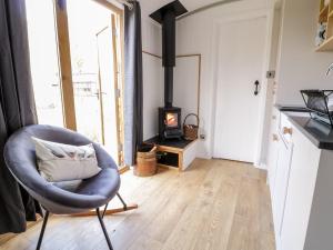 a living room with a chair and a wood stove at Betws View, Shepherd Hut in Betws-y-coed