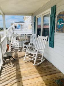 un porche con mecedoras blancas en una casa en Wayne's World, en Holden Beach