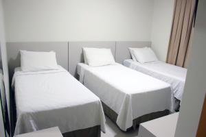 a hotel room with two beds and two nightstands at Sudoeste Hotel in Goiânia