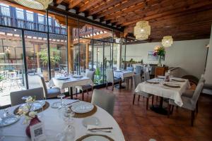 a restaurant with white tables and chairs and windows at Hotel Casa Palacio Uclés in Uclés