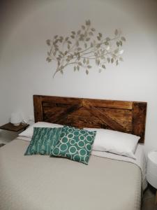 un letto con testiera in legno e cuscino verde di Tre Orologi a Piombino