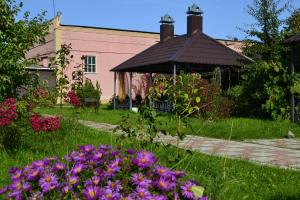 un jardín con flores púrpuras y cenador en Comfort Guest House, en Myshkin