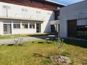 a building with two tables and a tree in the yard at Auberge de Jeunesse HI Pontarlier in Pontarlier