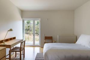 a bedroom with a bed and a desk and a window at Quinta da Caída in Arcas