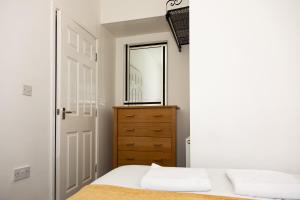 a bedroom with a bed and a dresser and a mirror at Alexander Apartments Roker in Sunderland