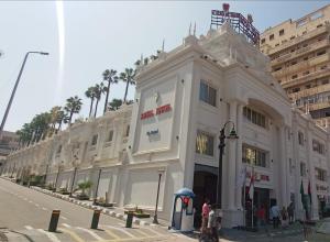Royal Jewel Al Raml Hotel في الإسكندرية: مبنى ابيض كبير على جانب شارع
