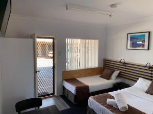 a hotel room with two beds and a balcony at Baths Motel Moree in Moree