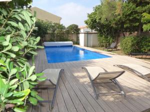 a swimming pool with two chairs on a wooden deck at Villa T6, 10 couchages, front de mer, piscine, Saint Pierre la Mer in Saint Pierre La Mer