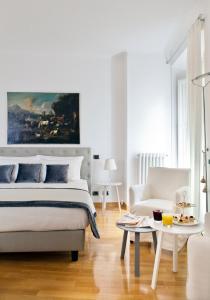 - une chambre blanche avec un lit et un canapé dans l'établissement Garibaldi Suites Piazza Di Spagna, à Rome