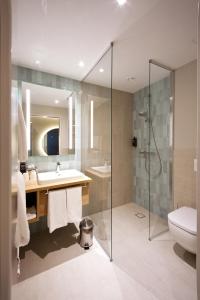 y baño con ducha, lavabo y aseo. en ibis Styles Parndorf Neusiedler See en Parndorf