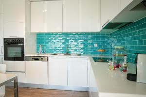 a kitchen with white cabinets and blue tiles at Marlin House IV in Ferrel