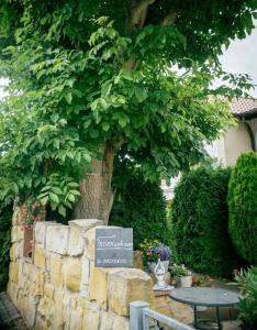 a tree with a sign next to a stone wall at Ferienwohnung "Zum Köpfel"- Wiesenthal in der Rhön in Wiesenthal