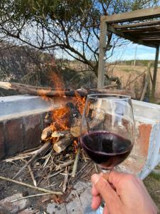 una persona che tiene un bicchiere di vino davanti al fuoco di Loft de Mar a José Ignacio