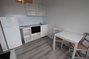 a small kitchen with a white table and a white refrigerator at Schlafhaus Dünenweg 16 in Heringsdorf