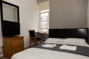 a bedroom with a bed with a television and a chair at South Shields Central in South Shields