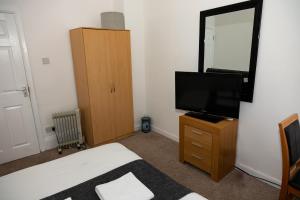 a bedroom with a bed and a television on a dresser at South Shields Central in South Shields