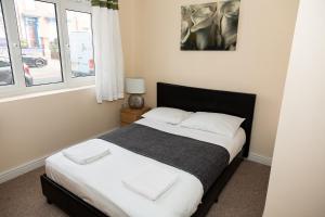 a bedroom with a bed with white sheets and a window at South Shields Central in South Shields