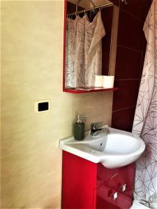 uma casa de banho com um lavatório branco e um armário vermelho em Guest House Loriano em Marcianise