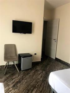 um quarto com uma cadeira e uma televisão na parede em Guest House Loriano em Marcianise