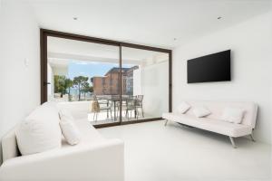a white living room with a white couch and a tv at Sa Nacra in Alcudia