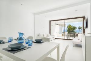 a white dining room with a white table and chairs at Sa Nacra in Alcudia