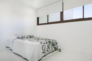 a white bedroom with a bed and a window at Sa Nacra in Alcudia