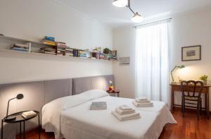 una camera da letto con un letto bianco e asciugamani di Suite La Pergola - Centro Storico a Catania