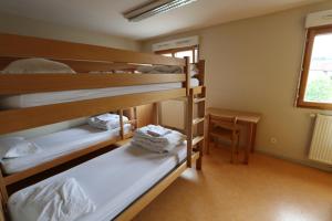 a room with three bunk beds and a table at Auberge de Jeunesse HI Pontarlier in Pontarlier