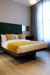 a bedroom with a large bed with a yellow blanket at CG Kensington in London