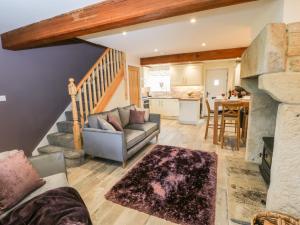 a living room with a couch and a kitchen at Mirk Cottage in Hebden Bridge