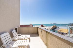 Un balcón con sillas y vistas al océano. en Residencial SKS, en Bombinhas