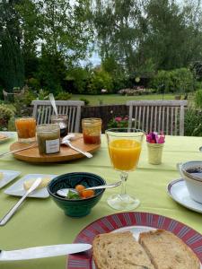 a table with a plate of bread and a glass of orange juice at A la Maison du Héron in Villeneuve d'Ascq