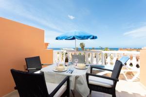 uma mesa com cadeiras e um guarda-sol azul numa varanda em Las Americas Royal em Playa de las Americas