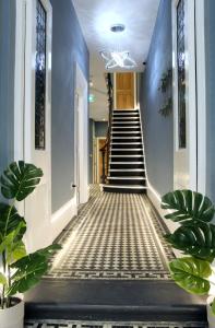 un couloir avec des murs bleus et des escaliers avec des plantes dans l'établissement CG Kensington, à Londres