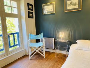 a bedroom with a blue chair sitting next to a bed at Druides 2 in Carnac