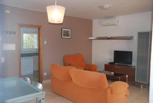 Sala de estar con 2 sillas de color naranja y TV en Chalet turistico Ametlla de Mar en Les tres Cales