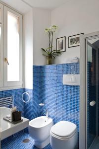La salle de bains est pourvue de carrelage bleu, de toilettes et d'un lavabo. dans l'établissement Garibaldi Suites Piazza Di Spagna, à Rome