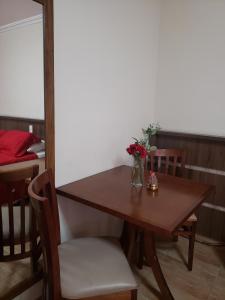 a table and chairs with a vase of flowers on it at Grand Enio Hotel e Cantina in Varginha