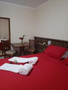 a bedroom with a red bed with towels on it at Grand Enio Hotel e Cantina in Varginha
