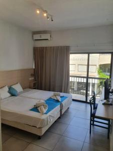 a bedroom with two beds and a desk and a window at Sea CleoNapa Mandali in Ayia Napa +40 photos