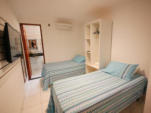Duas camas num pequeno quarto com um espelho em Pousada Brasileira em Porto de Galinhas