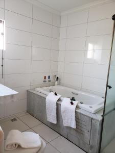 a white bathroom with a tub and two towels at Grand Enio Hotel e Cantina in Varginha