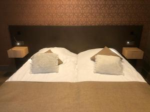 Una cama con sábanas blancas y almohadas. en Hotel Duivels Paterke Harelbeeksestraat 29, 8500 Kortrijk, en Cortrique