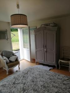 a bedroom with a bed and a chair and a cabinet at Kerlan in Béganne