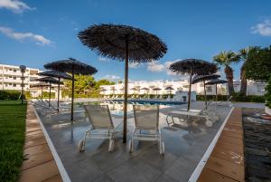 a row of chairs and umbrellas next to a pool at Camelina Suites in San Antonio Bay
