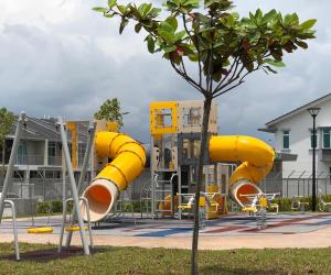 a yellow slide in a park with a tree at The Crib @ Desaru in Desaru