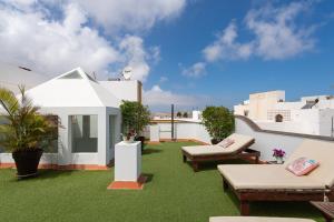 a rooftop patio with green grass and white buildings at The Yellow House - Solarium - Climatized Pool in Gáldar