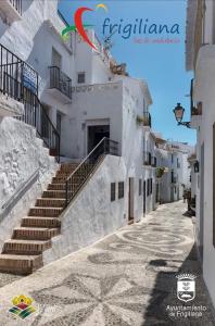 a street in a town with white buildings and stairs at Casa David in Frigiliana