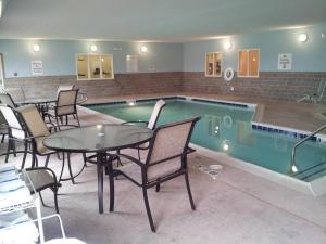 a pool with a table and chairs in it at Holiday Inn Express - Albert Lea, an IHG Hotel in Albert Lea